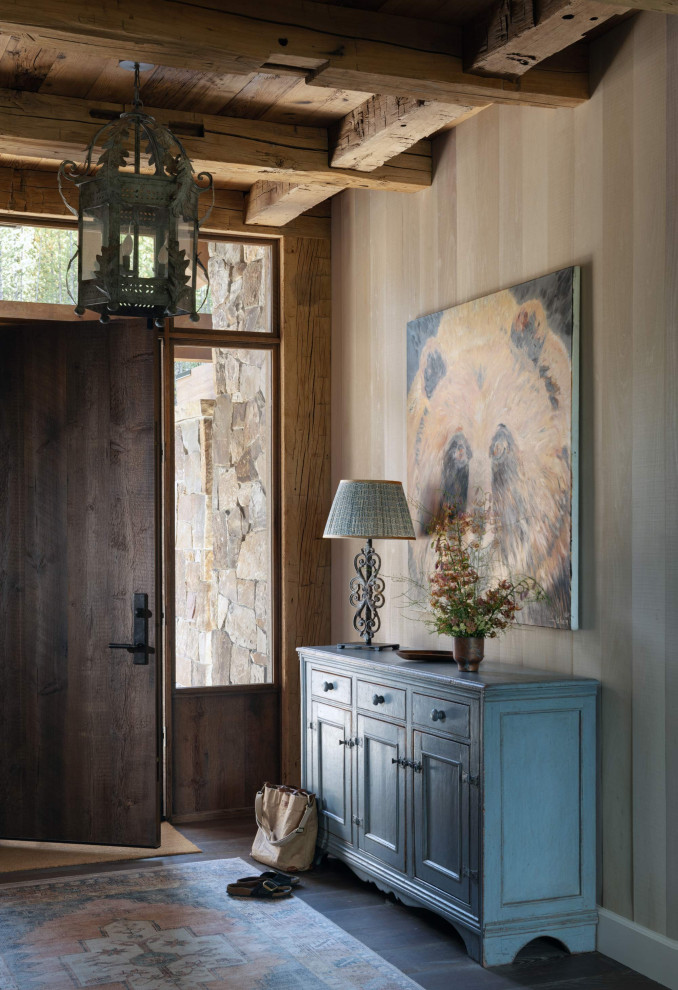 Example of a mountain style dark wood floor, exposed beam and wood wall front door design with a dark wood front door