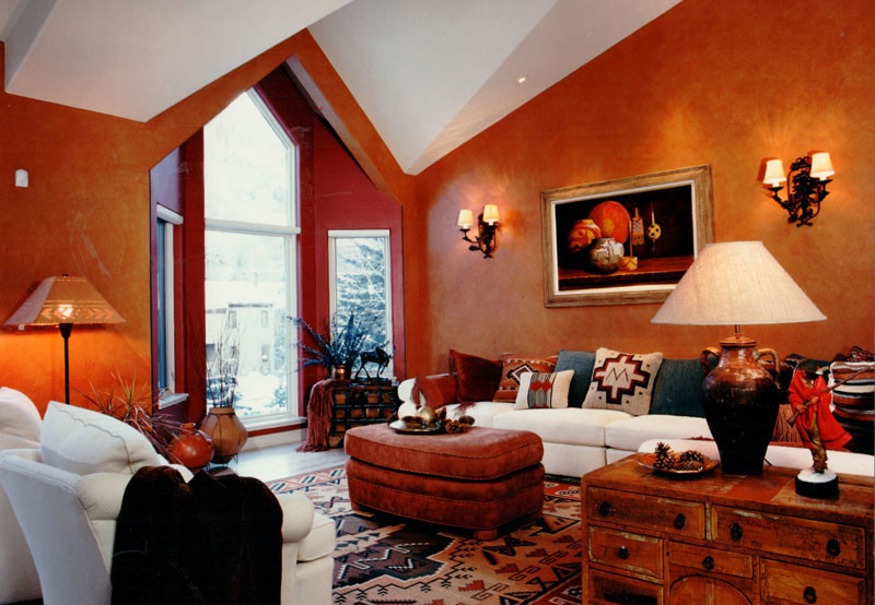 This is an example of a mid-sized country family room in Albuquerque with orange walls, light hardwood floors and no fireplace.