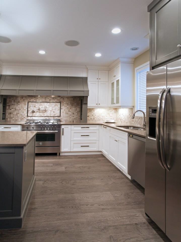 This is an example of a transitional eat-in kitchen in Calgary with an undermount sink, shaker cabinets, white cabinets, quartzite benchtops, black splashback, mosaic tile splashback, stainless steel appliances and medium hardwood floors.