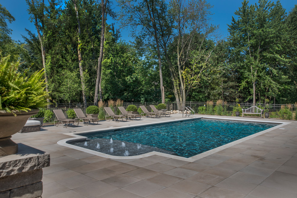 Photo of a mid-sized traditional backyard rectangular lap pool in Chicago with a water feature and concrete pavers.
