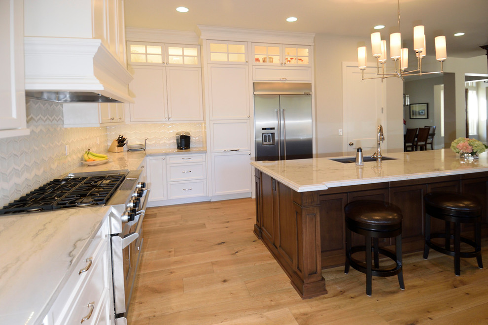 Eat-in kitchen - mid-sized transitional l-shaped medium tone wood floor eat-in kitchen idea with an undermount sink, recessed-panel cabinets, dark wood cabinets, granite countertops, gray backsplash, glass tile backsplash, stainless steel appliances and an island