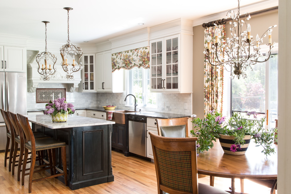 Eat-in kitchen - large transitional single-wall medium tone wood floor eat-in kitchen idea in Boston with a farmhouse sink, glass-front cabinets, white cabinets, granite countertops, gray backsplash, ceramic backsplash, stainless steel appliances and an island