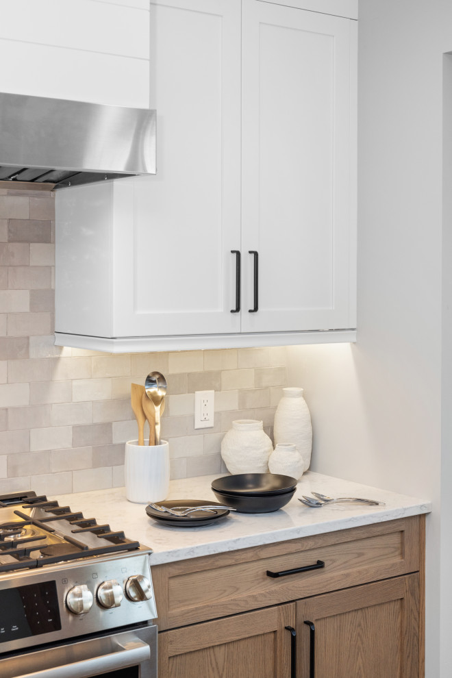 Example of a mid-sized transitional eat-in kitchen design with shaker cabinets, white cabinets, quartz countertops, gray backsplash, subway tile backsplash, stainless steel appliances, an island and white countertops
