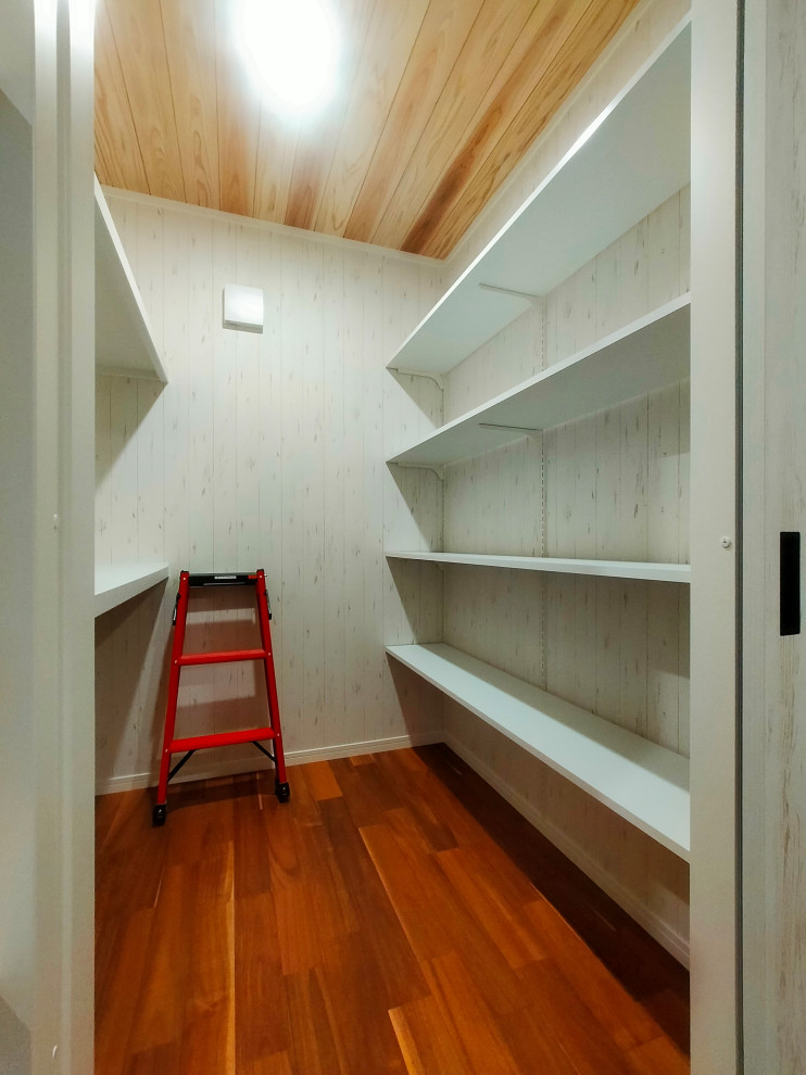 Immagine di una piccola cabina armadio unisex nordica con pavimento in legno verniciato, pavimento marrone e soffitto in legno
