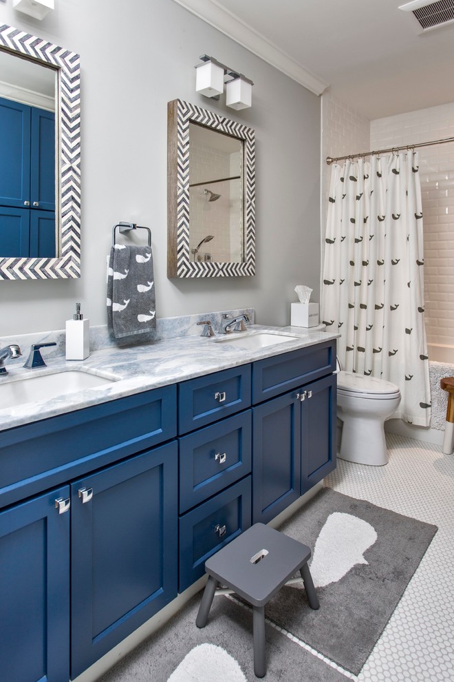 Photo of a large contemporary kids bathroom in Portland Maine with shaker cabinets, blue cabinets, white tile, subway tile, ceramic floors, marble benchtops, an alcove tub, a shower/bathtub combo, a two-piece toilet, grey walls and an undermount sink.
