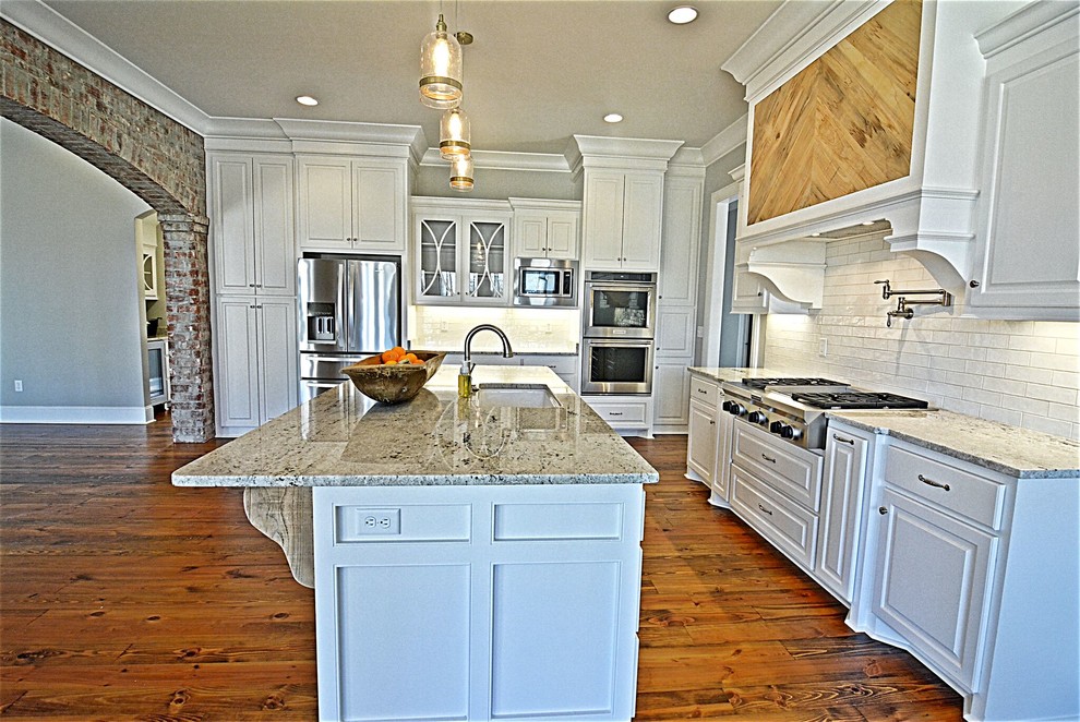 Eat-in kitchen - mid-sized transitional u-shaped medium tone wood floor and brown floor eat-in kitchen idea in Jackson with an undermount sink, raised-panel cabinets, white cabinets, granite countertops, white backsplash, subway tile backsplash, stainless steel appliances and an island