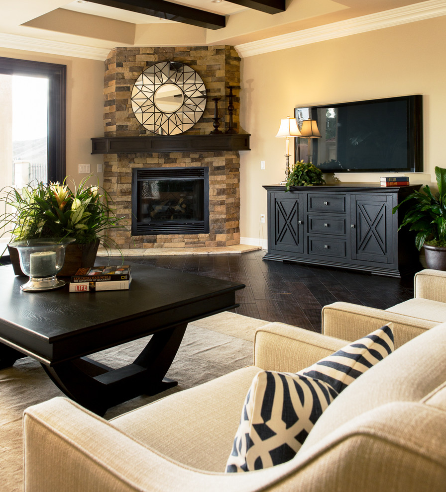 Inspiration for a mid-sized transitional open concept family room in Orange County with beige walls, dark hardwood floors, a corner fireplace, a stone fireplace surround, a wall-mounted tv and brown floor.