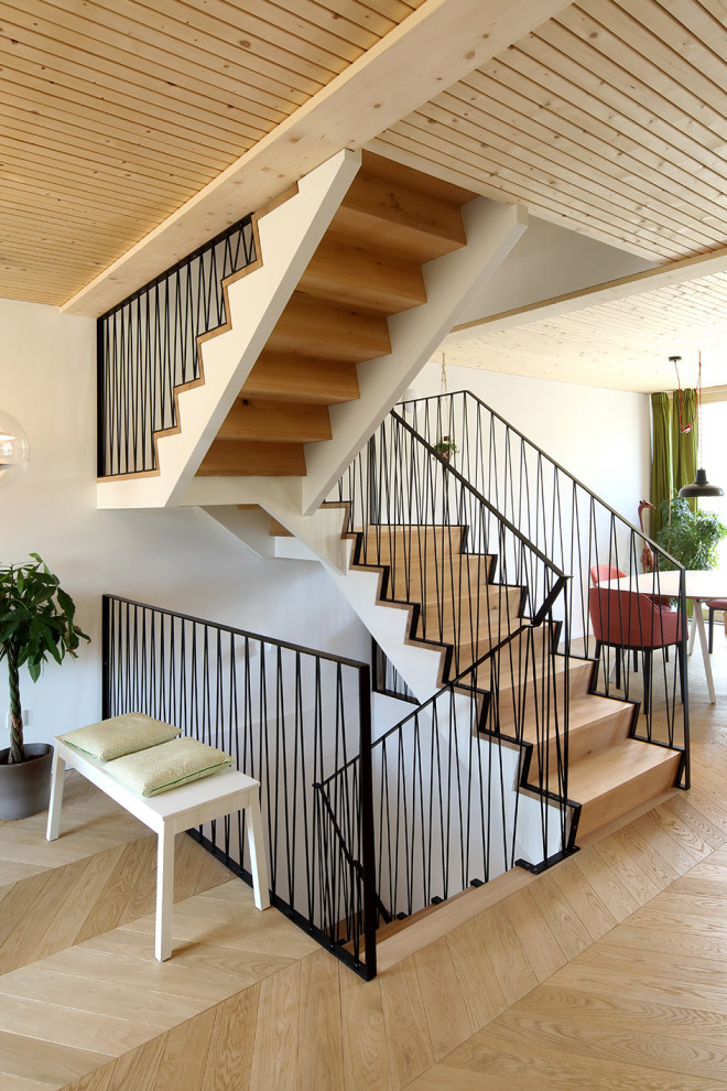 Design ideas for a mid-sized contemporary wood u-shaped staircase in Munich with limestone risers and wood railing.