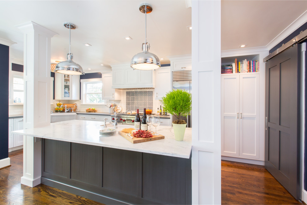 Design ideas for a traditional l-shaped kitchen in San Francisco with a farmhouse sink, shaker cabinets, white cabinets, stainless steel appliances, dark hardwood floors, with island, brown floor and white benchtop.