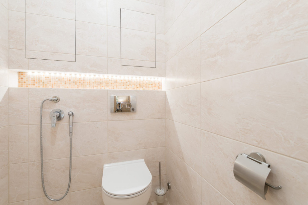 Inspiration för ett mellanstort funkis en-suite badrum, med släta luckor, vita skåp, ett badkar i en alkov, en dusch/badkar-kombination, en vägghängd toalettstol, beige kakel, beige väggar, klinkergolv i keramik, ett integrerad handfat och beiget golv