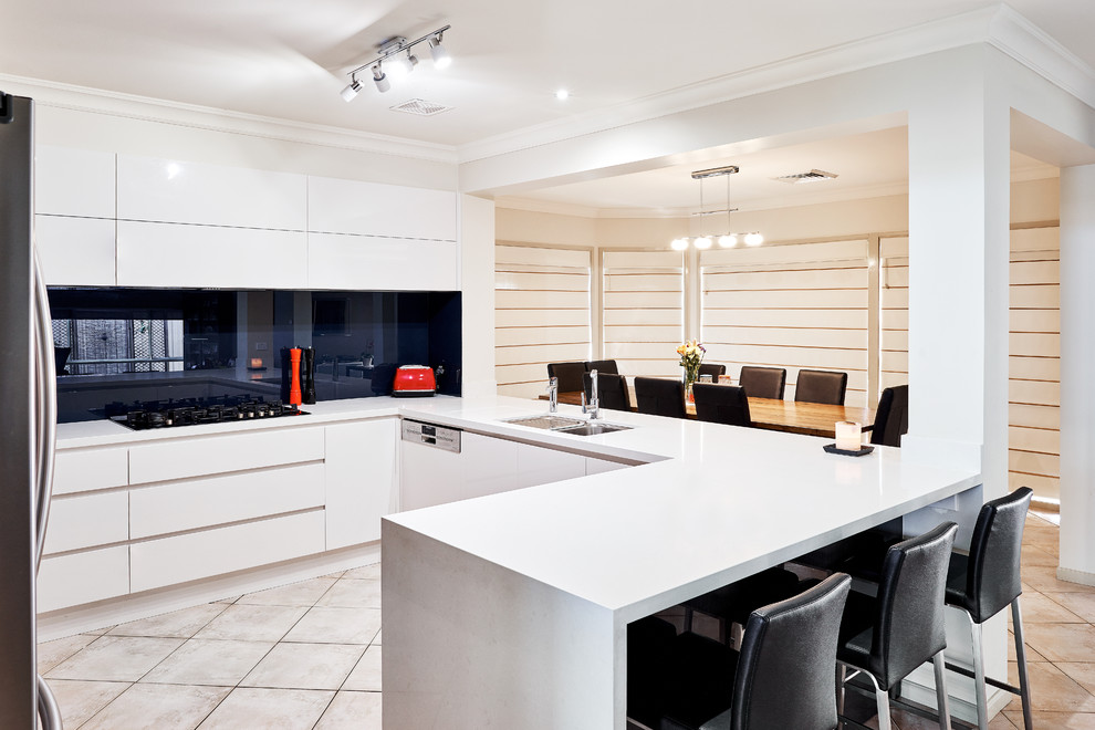 Photo of a large modern u-shaped open plan kitchen in Sydney with a double-bowl sink, grey cabinets, quartz benchtops, blue splashback, glass sheet splashback, stainless steel appliances, ceramic floors and a peninsula.