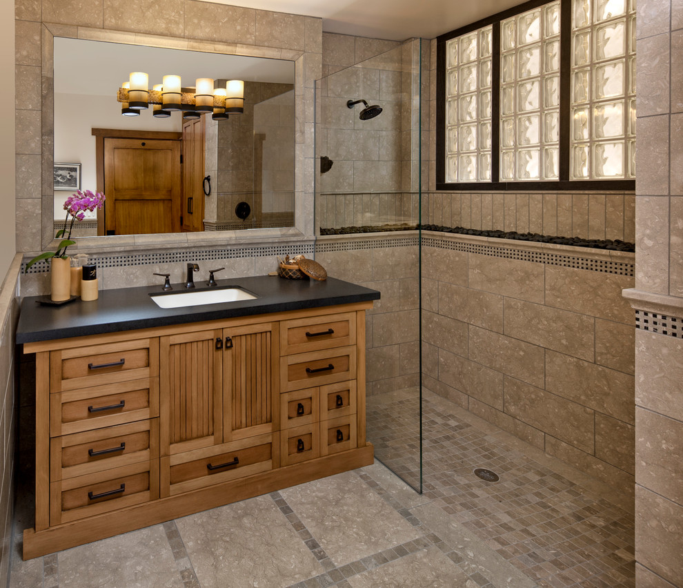 This is an example of a mid-sized asian bathroom in Santa Barbara with an undermount sink, medium wood cabinets, a curbless shower, beige tile, stone tile, limestone floors and recessed-panel cabinets.