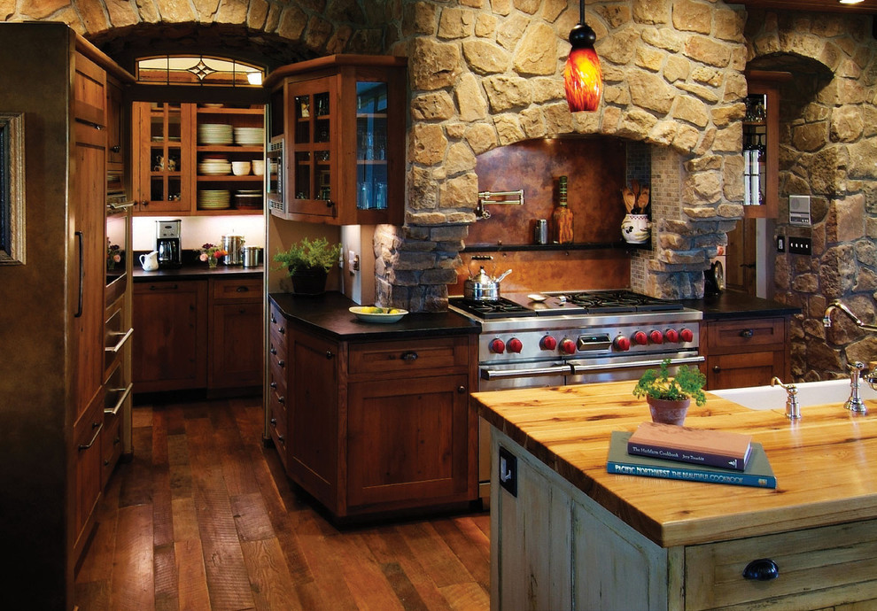 Inspiration for a country kitchen in Denver with dark wood cabinets, brown splashback, stainless steel appliances, a drop-in sink, recessed-panel cabinets, wood benchtops, stone slab splashback, dark hardwood floors and with island.