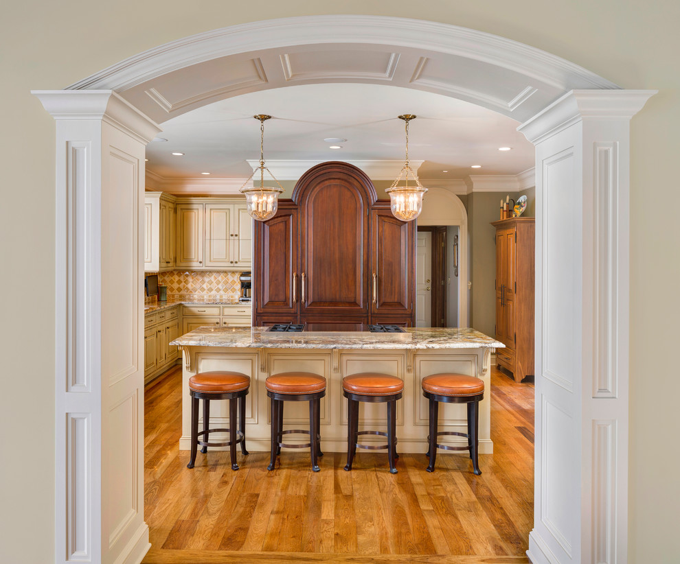 This is an example of a large traditional l-shaped eat-in kitchen in Kansas City with raised-panel cabinets, distressed cabinets, granite benchtops, multi-coloured splashback, glass tile splashback, light hardwood floors and with island.