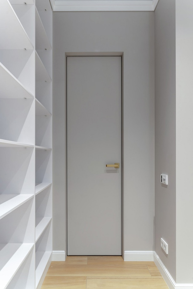 Diseño de armario vestidor unisex actual grande con puertas de armario de madera clara, suelo de baldosas de porcelana y suelo beige