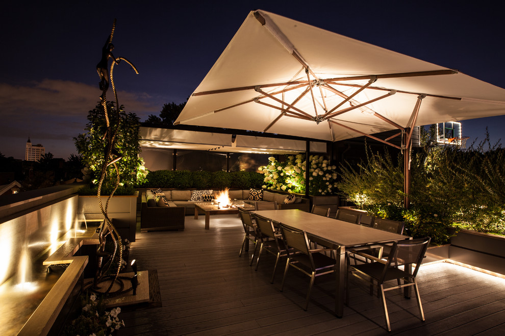 This is an example of a mid-sized contemporary rooftop and rooftop deck in Chicago with a fire feature and an awning.