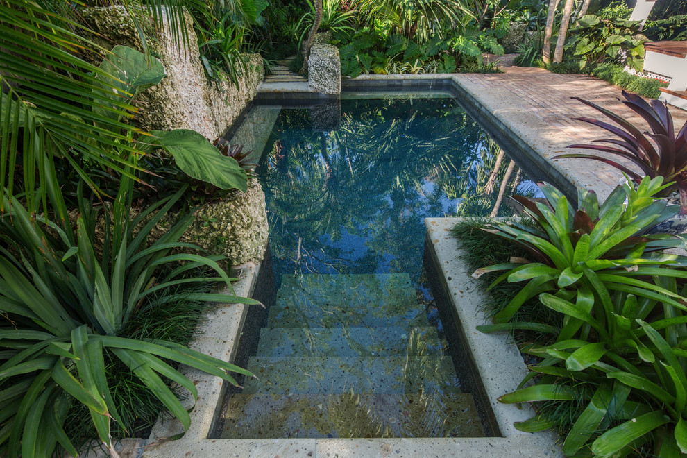 This is an example of a mid-sized tropical side yard full sun garden in Miami with brick pavers.
