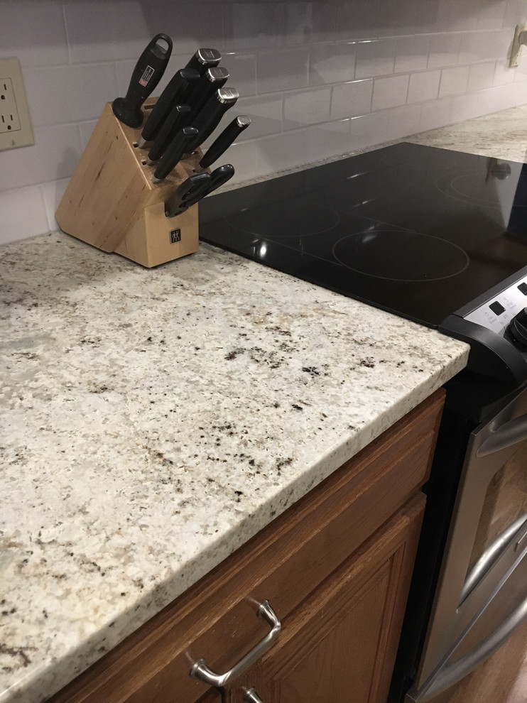 Large transitional u-shaped medium tone wood floor eat-in kitchen photo with an undermount sink, raised-panel cabinets, medium tone wood cabinets, granite countertops, white backsplash, ceramic backsplash, stainless steel appliances and an island