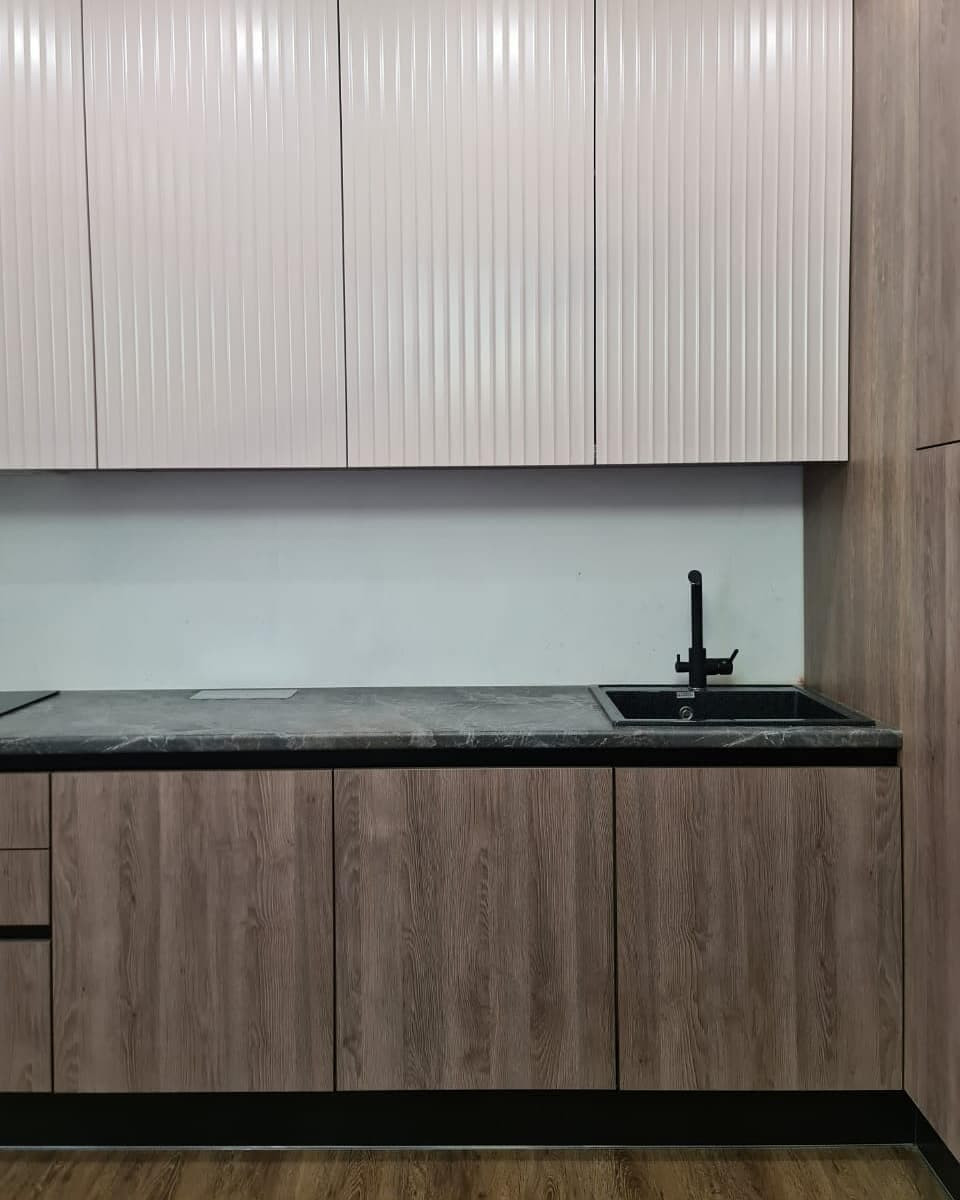 Большая угловая кухня в сером цвете с рифлеными фасадами и витриной