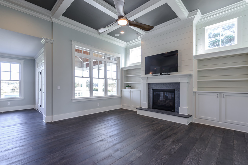 Photo of a mid-sized transitional open concept family room in Other with grey walls, dark hardwood floors, a standard fireplace, a stone fireplace surround, a wall-mounted tv and grey floor.