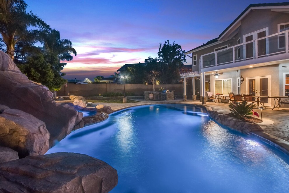 This is an example of a large transitional backyard custom-shaped pool in Orange County with a water slide and concrete pavers.
