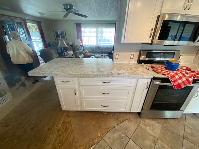 Large galley eat-in kitchen photo with shaker cabinets, white cabinets, laminate countertops, a peninsula and white countertops