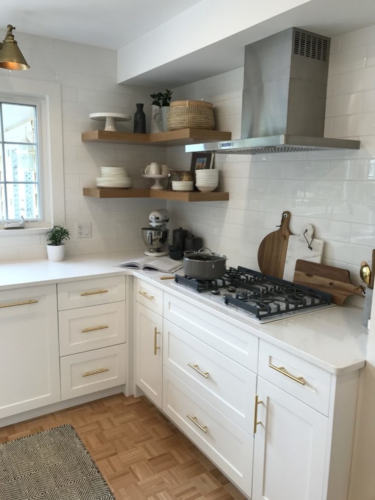 Design ideas for a small transitional l-shaped separate kitchen in Other with an undermount sink, shaker cabinets, white cabinets, quartz benchtops, white splashback, ceramic splashback, stainless steel appliances, light hardwood floors, with island, brown floor and white benchtop.