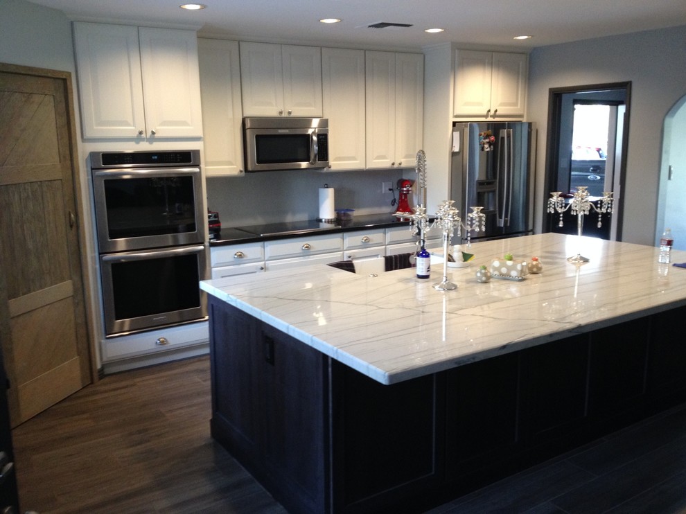 Eat-in kitchen - mid-sized transitional u-shaped dark wood floor eat-in kitchen idea in Phoenix with a double-bowl sink, raised-panel cabinets, dark wood cabinets, wood countertops, white backsplash, subway tile backsplash, white appliances and no island