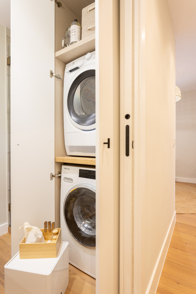 This is an example of a small traditional laundry cupboard in Madrid with ceramic floors and a stacked washer and dryer.