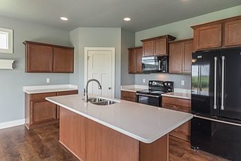 Eat-in kitchen - mid-sized transitional l-shaped medium tone wood floor eat-in kitchen idea with an undermount sink, recessed-panel cabinets, medium tone wood cabinets, quartz countertops, black appliances and an island