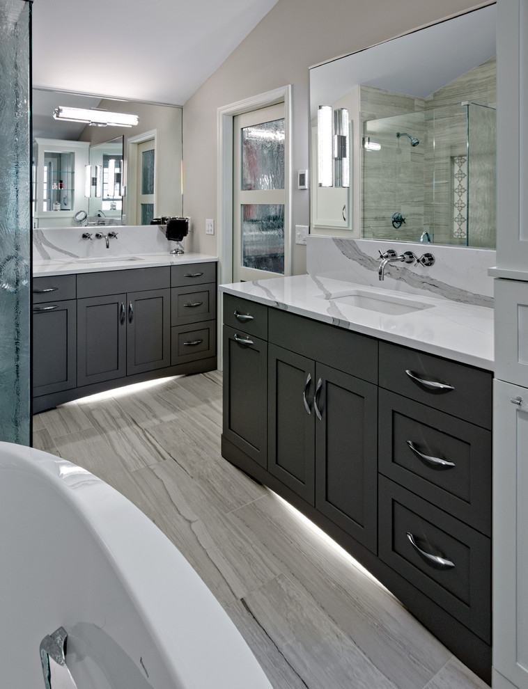 Design ideas for a large contemporary master bathroom in Minneapolis with shaker cabinets, grey cabinets, a freestanding tub, a corner shower, a two-piece toilet, gray tile, porcelain tile, grey walls, porcelain floors, an undermount sink, engineered quartz benchtops, grey floor, a hinged shower door and white benchtops.