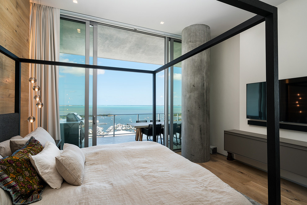 This is an example of a contemporary bedroom in Miami with white walls, medium hardwood floors and brown floor.