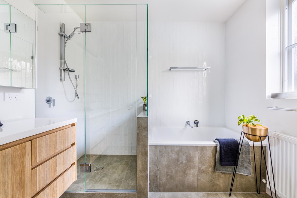 This is an example of a mid-sized contemporary bathroom in Melbourne with a drop-in tub, a one-piece toilet, white tile, ceramic tile, white walls, porcelain floors, a drop-in sink, engineered quartz benchtops, a hinged shower door and white benchtops.