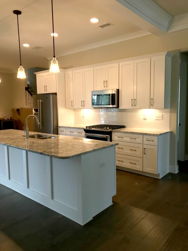 Example of a mid-sized transitional single-wall dark wood floor and brown floor eat-in kitchen design with a double-bowl sink, shaker cabinets, white cabinets, granite countertops, white backsplash, subway tile backsplash, stainless steel appliances, an island and brown countertops