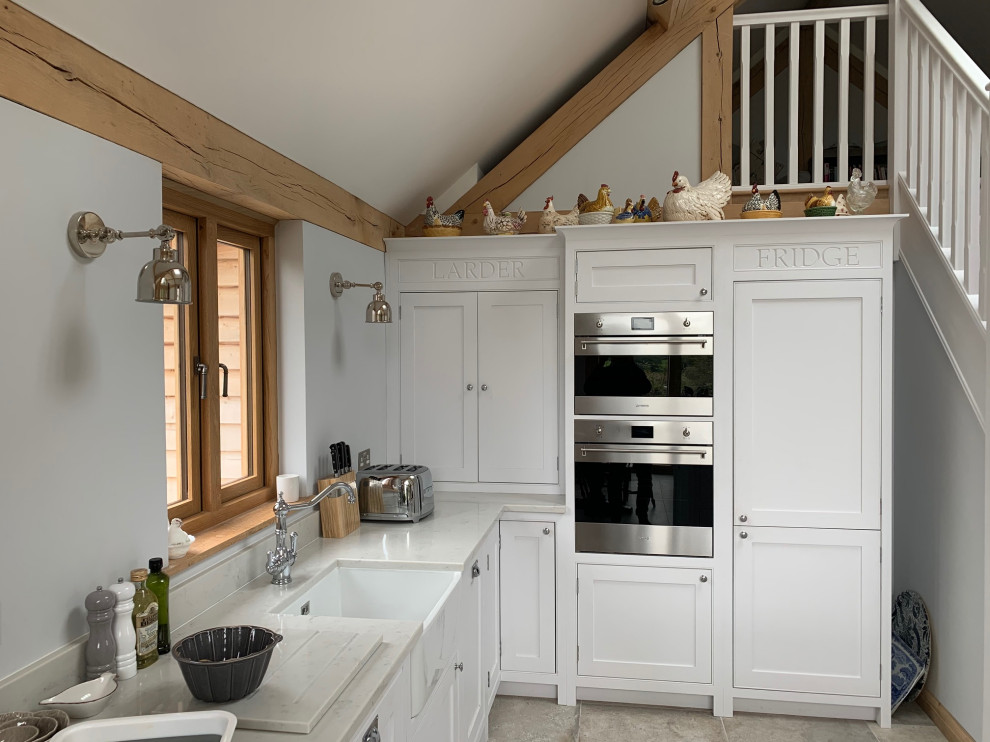 Inspiration for a country l-shaped kitchen in Surrey with beaded inset cabinets, white cabinets, quartzite benchtops, white benchtop, a farmhouse sink, stainless steel appliances, grey floor and vaulted.