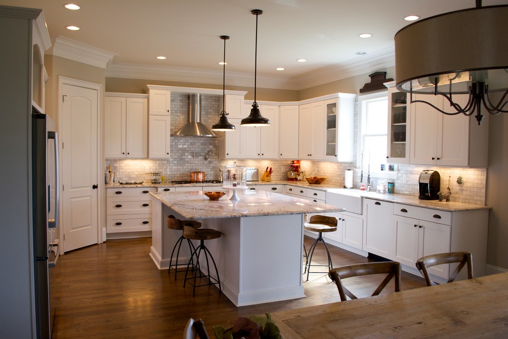 Design ideas for a mid-sized traditional u-shaped eat-in kitchen in Raleigh with a farmhouse sink, shaker cabinets, white cabinets, granite benchtops, grey splashback, stone tile splashback, stainless steel appliances, medium hardwood floors, with island and brown floor.