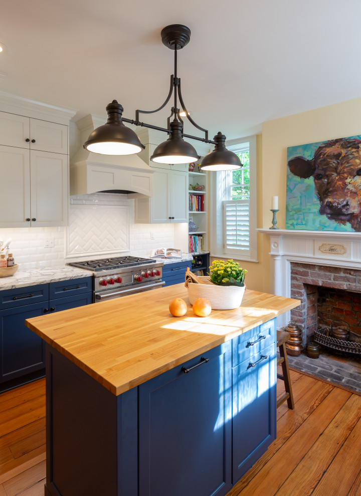 Photo of a traditional kitchen in Richmond with recessed-panel cabinets, blue cabinets, white splashback, subway tile splashback, stainless steel appliances, medium hardwood floors, with island, brown floor and white benchtop.