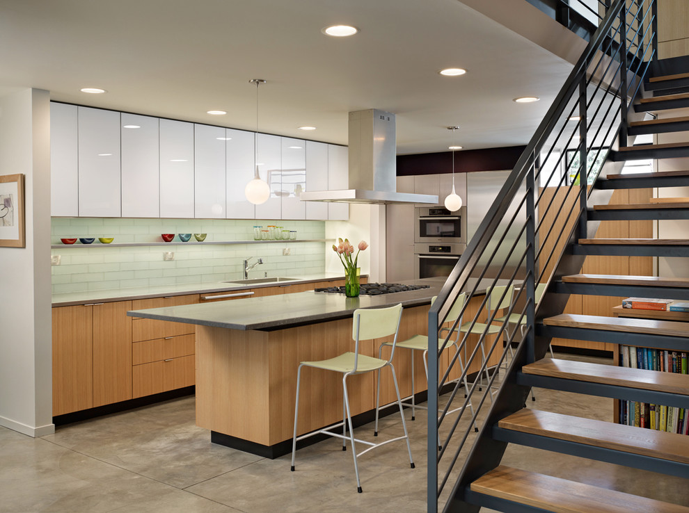 Midcentury u-shaped eat-in kitchen in Seattle with a drop-in sink, flat-panel cabinets, medium wood cabinets, soapstone benchtops, glass tile splashback and stainless steel appliances.