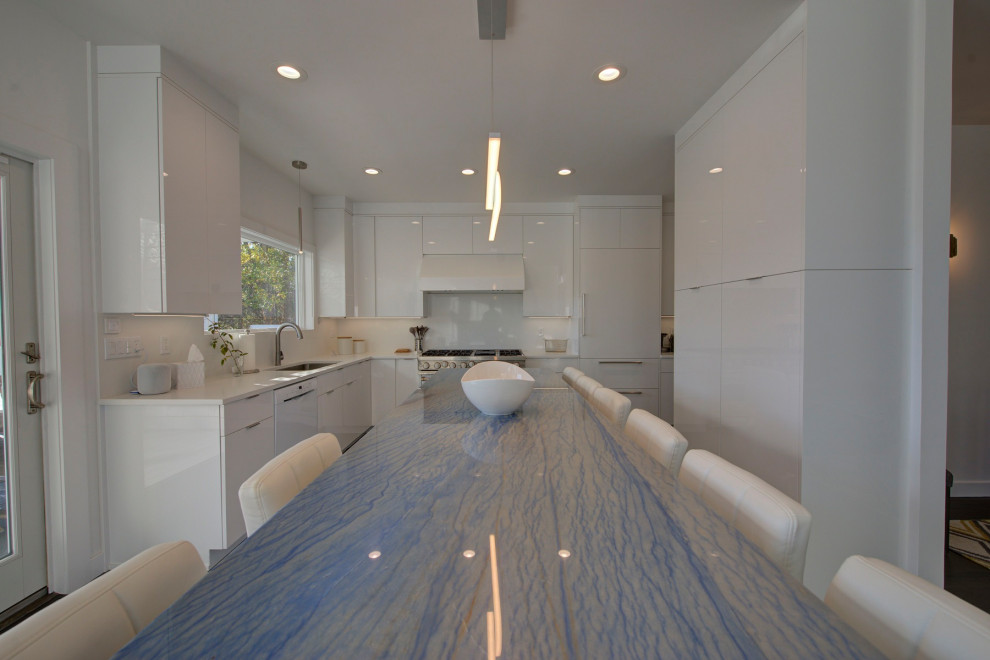 Example of a large minimalist u-shaped medium tone wood floor and brown floor open concept kitchen design in New York with an undermount sink, flat-panel cabinets, white cabinets, quartzite countertops, white backsplash, porcelain backsplash, stainless steel appliances, an island and blue countertops