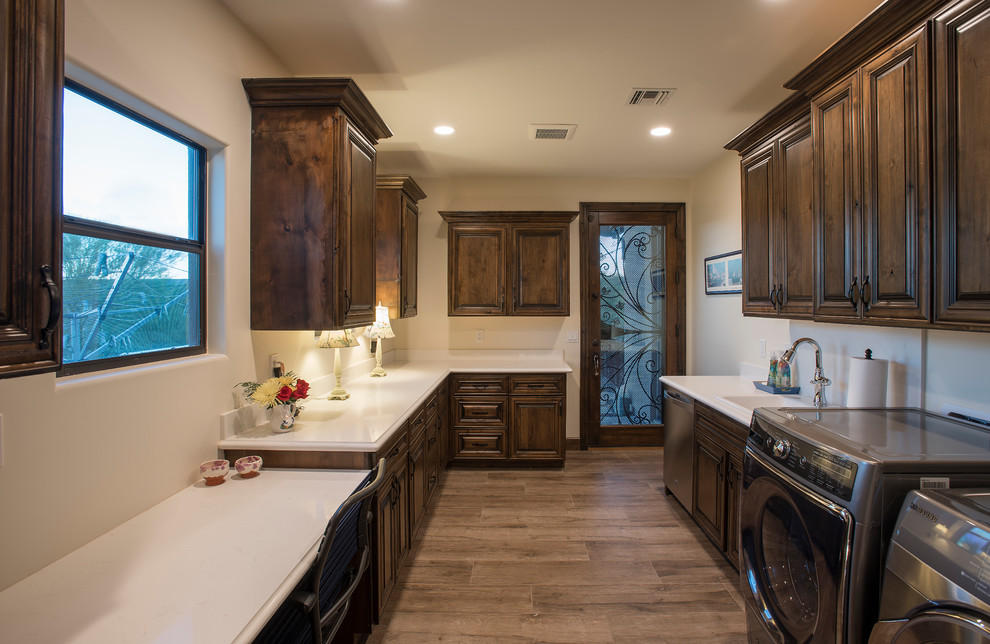 This is an example of a large country u-shaped utility room in Phoenix with an undermount sink, raised-panel cabinets, dark wood cabinets, quartz benchtops, beige walls, medium hardwood floors, a side-by-side washer and dryer, brown floor and turquoise benchtop.