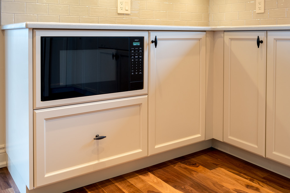Example of a large transitional medium tone wood floor eat-in kitchen design in Calgary with recessed-panel cabinets, beige cabinets, beige backsplash, subway tile backsplash and an island