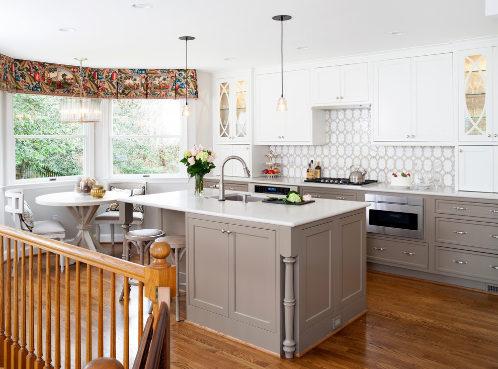 This is an example of a mid-sized transitional l-shaped eat-in kitchen in DC Metro with white cabinets, white splashback, stainless steel appliances and with island.