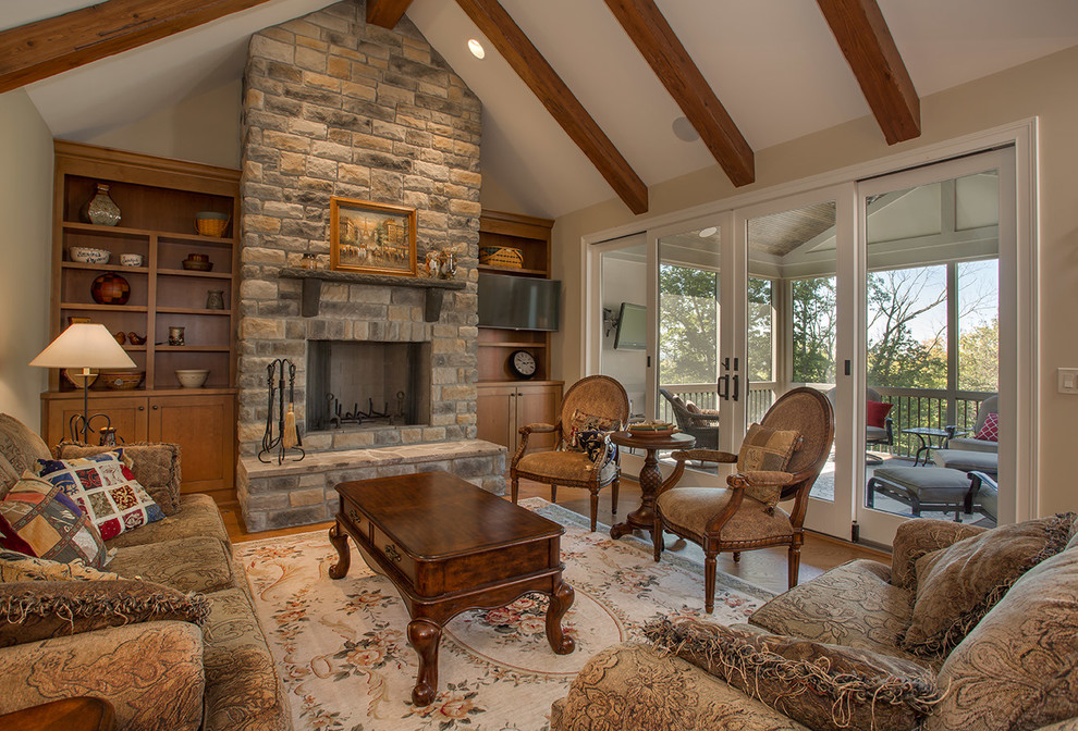 This is an example of a mid-sized traditional open concept family room in Cincinnati with beige walls, medium hardwood floors, a standard fireplace, a stone fireplace surround and a wall-mounted tv.