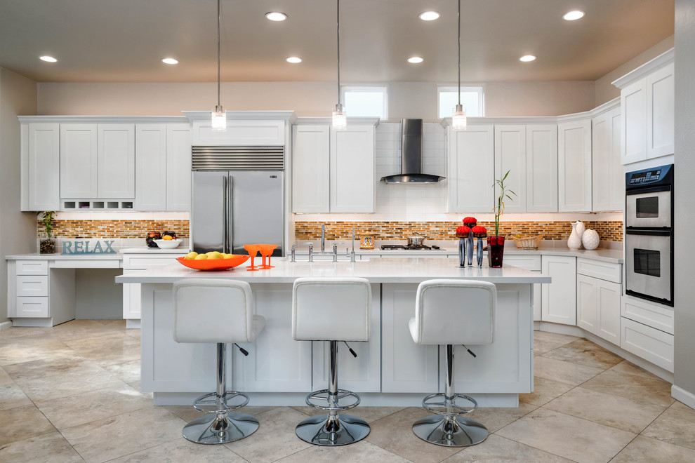 Large transitional kitchen in Phoenix with shaker cabinets, white cabinets, quartz benchtops, stainless steel appliances, travertine floors, with island, multi-coloured splashback and mosaic tile splashback.