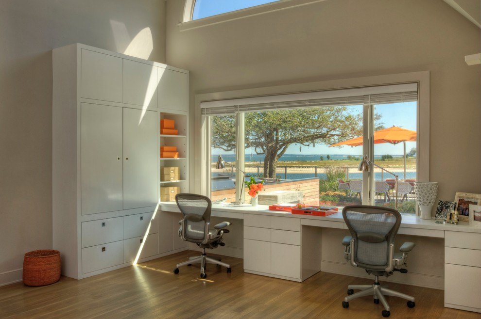 Photo of a beach style home office in New York with beige walls, medium hardwood floors and a built-in desk.