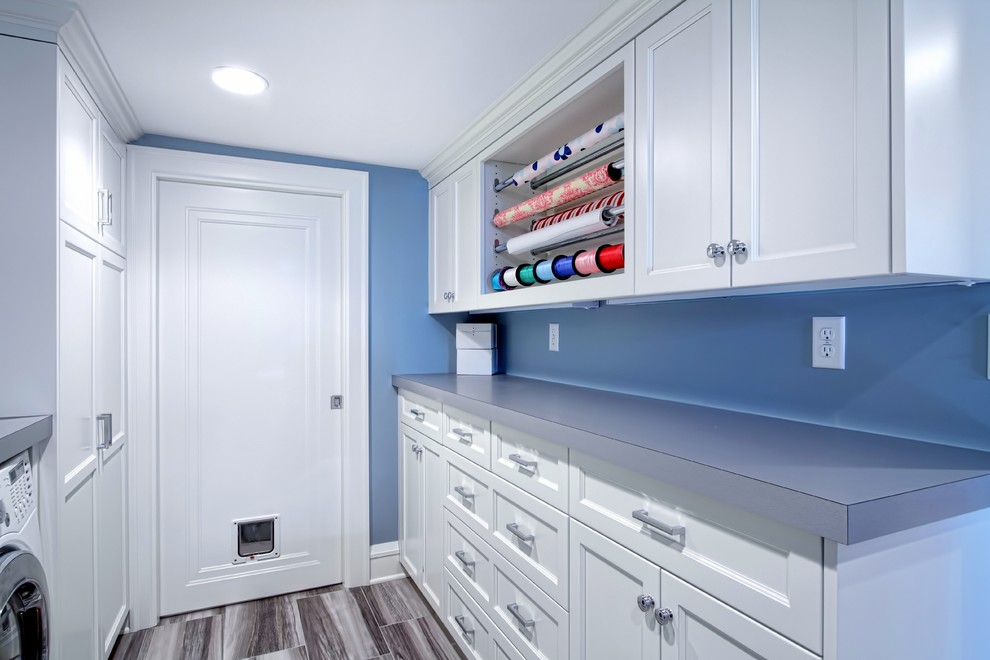 Mid-sized transitional utility room in Minneapolis with recessed-panel cabinets, white cabinets, laminate benchtops, blue walls, ceramic floors and a side-by-side washer and dryer.