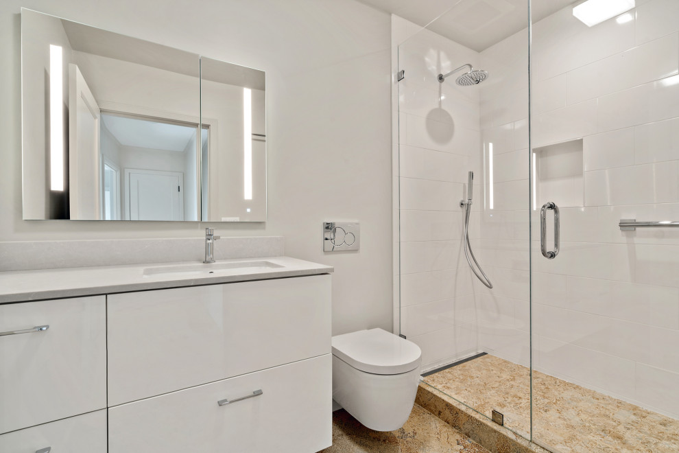 This is an example of a mid-sized midcentury master bathroom in San Francisco with flat-panel cabinets, white cabinets, an alcove shower, a wall-mount toilet, white tile, ceramic tile, white walls, marble floors, an undermount sink, solid surface benchtops, beige floor, a hinged shower door, white benchtops, a single vanity and a floating vanity.