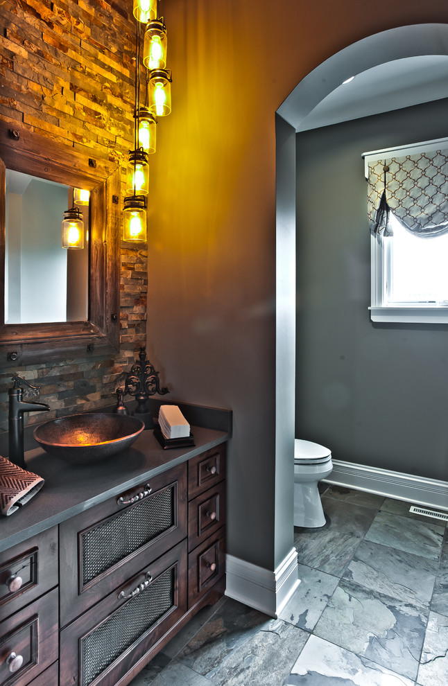 Design ideas for a mid-sized country 3/4 bathroom in Chicago with furniture-like cabinets, dark wood cabinets, a two-piece toilet, multi-coloured tile, stone tile, grey walls, slate floors, a vessel sink and soapstone benchtops.