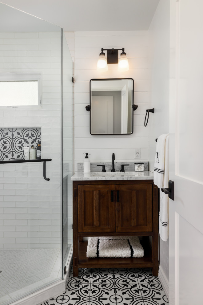 Inspiration for a small farmhouse 3/4 white tile and porcelain tile porcelain tile, multicolored floor, single-sink and shiplap wall corner shower remodel with white walls, recessed-panel cabinets, medium tone wood cabinets, a two-piece toilet, an undermount sink, quartz countertops, a hinged shower door, gray countertops, a niche and a built-in vanity