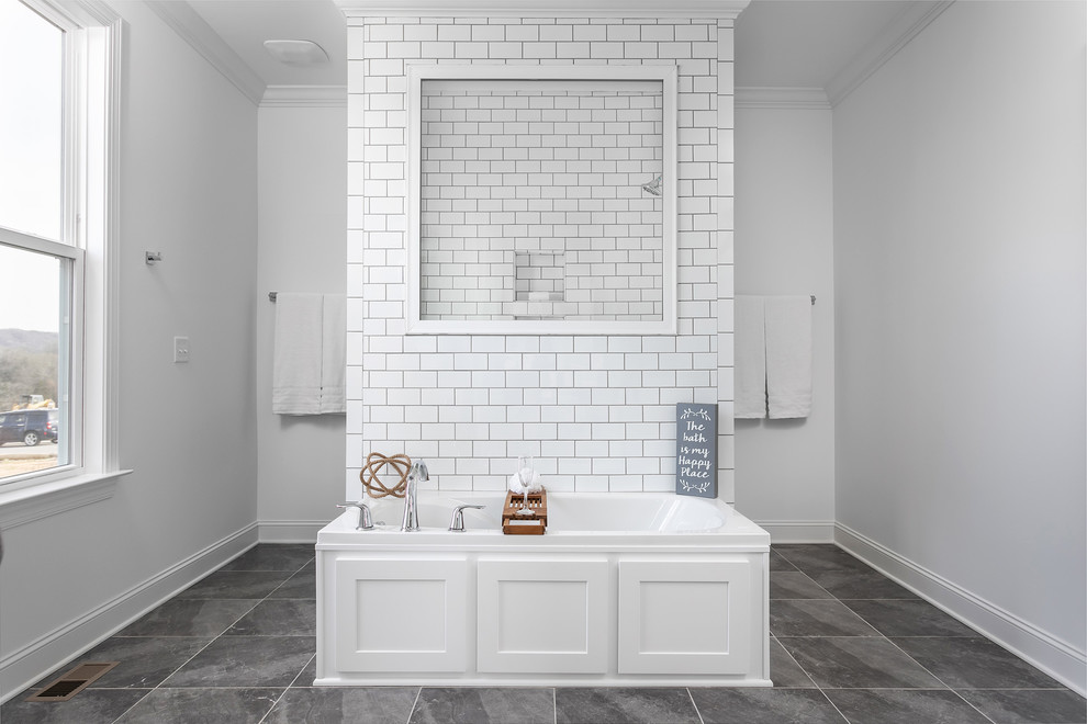 This is an example of a mid-sized contemporary master wet room bathroom in Other with shaker cabinets, white cabinets, a drop-in tub, white tile, subway tile, white walls, porcelain floors, an undermount sink, granite benchtops, black floor and multi-coloured benchtops.